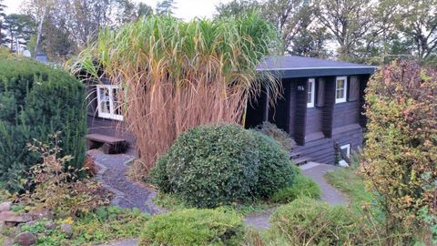 A pretty house with a dark facade, surrounded by lush plants and bushes. The garden is lovingly designed and creates a pleasant atmosphere.