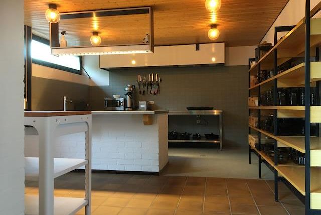 A modern kitchen with open shelves and a large window. The walls are bright, and the lighting creates an inviting atmosphere.