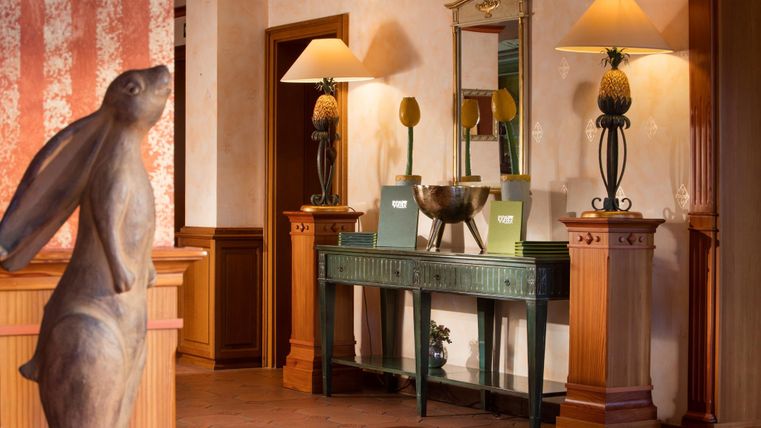 Een stijlvolle inrichting met een houten loper en warm licht. Een elegante commode met decoratie en lampen trekt de aandacht.