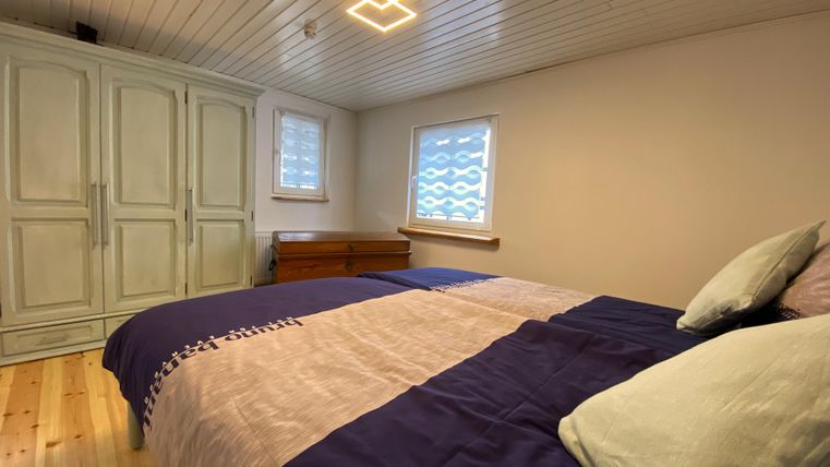 Een gezellige slaapkamer met een groot bed en lichte muren. De ruimte is goed verlicht en heeft een kast en een raam.