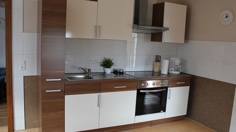 Modern kitchen with wood and white cabinets. It is clean and well-equipped with a stove, sink, and kitchen accessories.