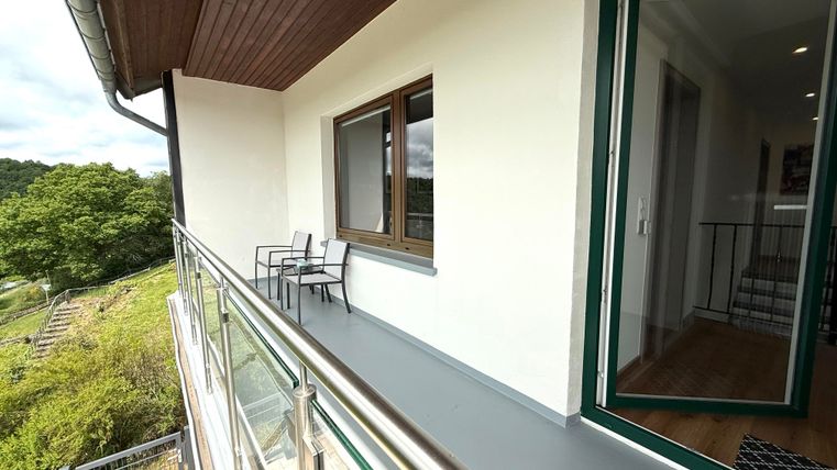 Een modern balkon met uitzicht op de natuur. Twee stoelen staan klaar om te ontspannen.