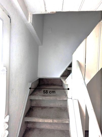 A staircase with carpet leads up. The width of the staircase is 58 cm.