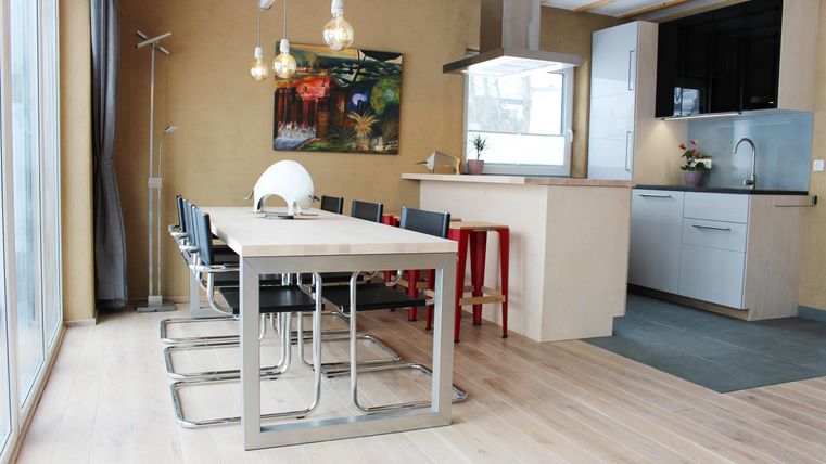 A modern dining room with a large table and black chairs. The bright kitchen is designed to be open and welcoming.