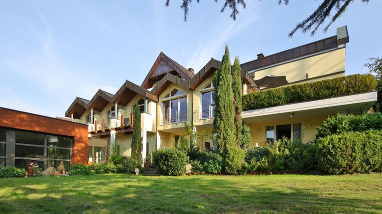 Een modern huis met een verzorgde tuin en grote ramen. De architectuur is aantrekkelijk en combineert houten en glaselementen.