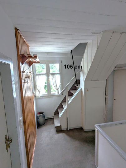 A bright hallway with a staircase and an adjoining room. The height of the staircase is 105 cm.