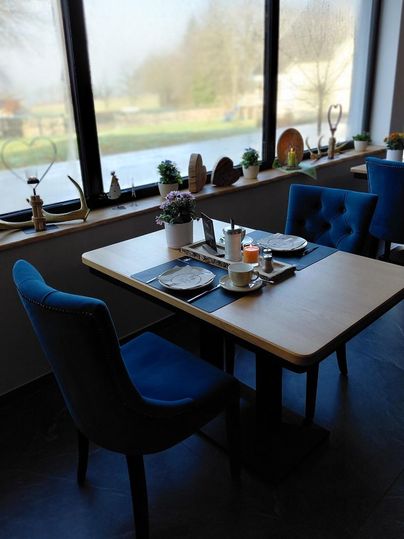 A cozy table in a modern restaurant, decorated with plants and dishes. Large windows provide a view of the outside.