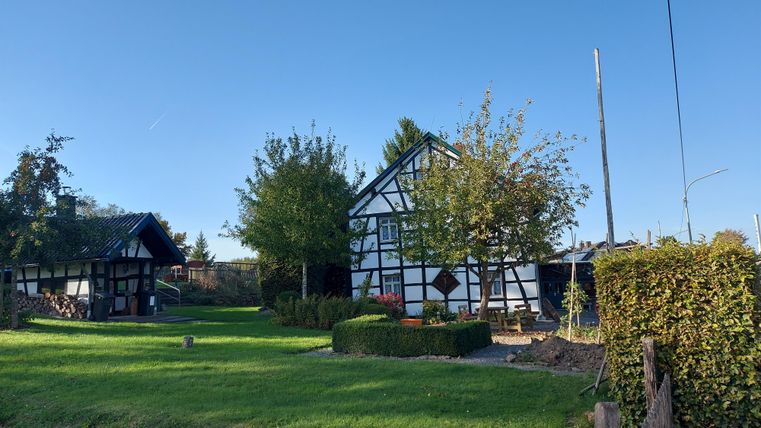 A pretty, traditional house with half-timbering and a large garden. The sky is clear and the surroundings are green and welcoming.
