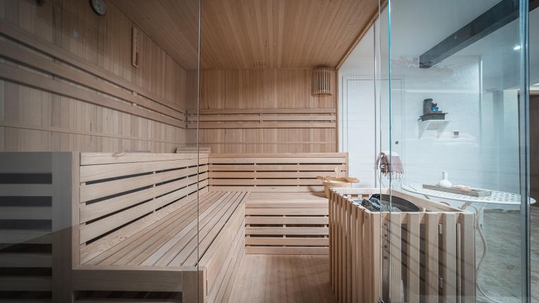 Een moderne sauna met houten wandpanelen en banken. De ruimte is helder en uitnodigend ingericht.