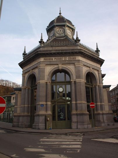 Een historisch gebouw met een markante architectuur en een koepeldak. De façade is rijk versierd en staat op een straathoek.