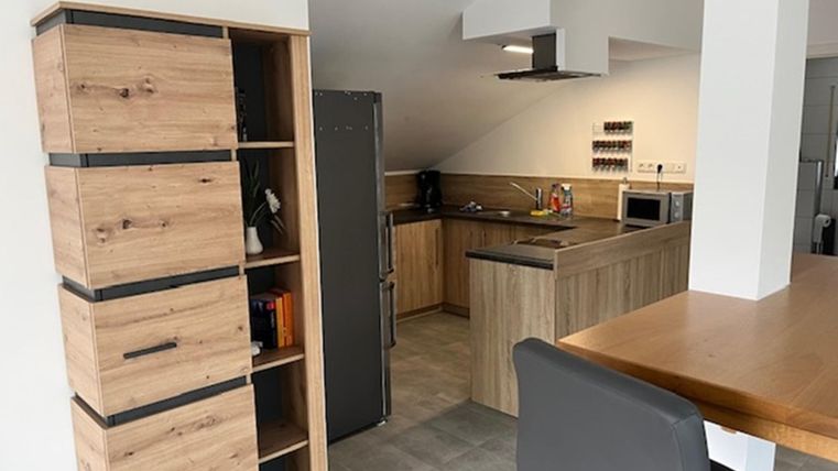 Een moderne keuken met houten planken en een keukenblok. De ruimte is licht en vriendelijk ingericht.