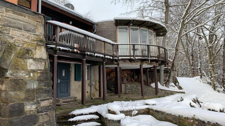 A modern wooden house in a snow-covered setting. The large terrace offers a beautiful view of the winter landscape.
