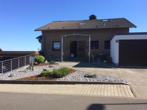 Ein modernes Haus mit einer eingängigen Fassade und einem gepflegten Vorgarten. Der Eingang ist klar strukturiert und die Umgebung ist ordentlich gestaltet.