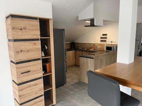 Een moderne keuken met houten planken en een groot werkblad. De ruimte heeft lichte kleuren en is goed georganiseerd.