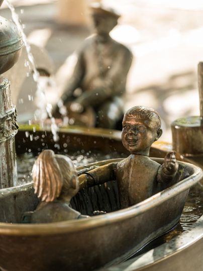 A beautiful bronze statue of two children in a bathtub. Water bubbles up from the surroundings, creating a vibrant atmosphere.