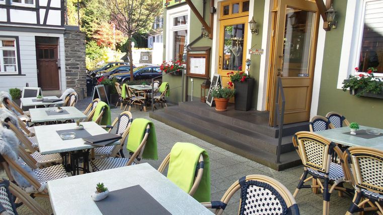 Een uitnodigend restaurant met tafels op het terras. De omgeving is groen en vriendelijk, perfect voor een maaltijd in de buitenlucht.