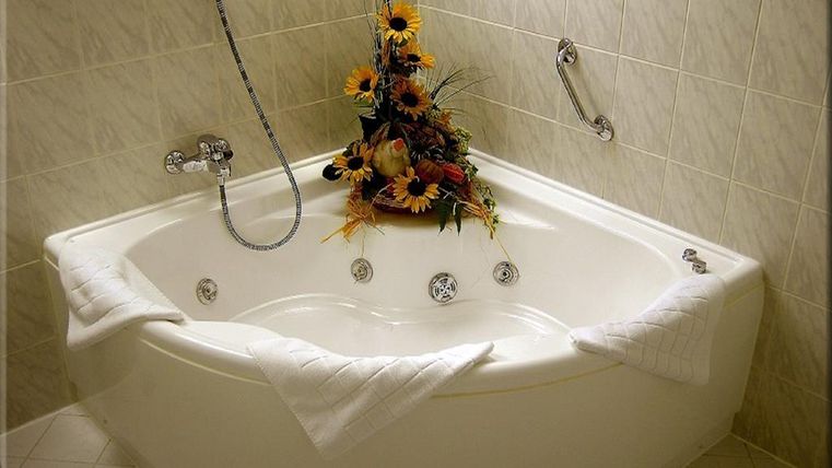 Eine luxuriöse Badewanne mit einer dekorativen Blumenarrangement. Die Wände sind mit eleganten Fliesen bekleidet.