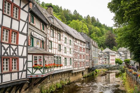 Ein malerisches Fachwerkhaus am Ufer eines ruhigen Flusses. Umgeben von grünen Bäumen und einer idyllischen Landschaft.