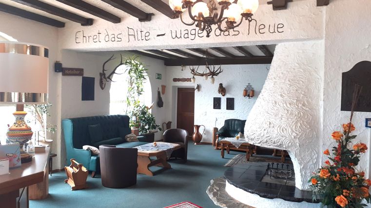 A cozy room with wooden beams and a modern fireplace. Comfortable seating and decorative rugs create an inviting atmosphere.
