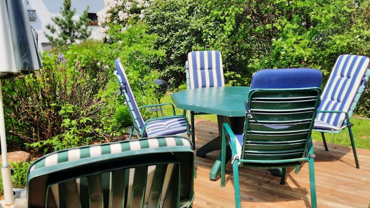 An inviting seating area in the garden with a round table and several chairs. Surrounded by lush greenery and plants.