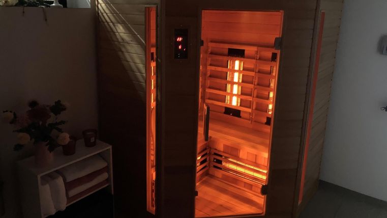 Een moderne sauna van hout met warm, oranje licht. De inrichting is gezellig en uitnodigend.