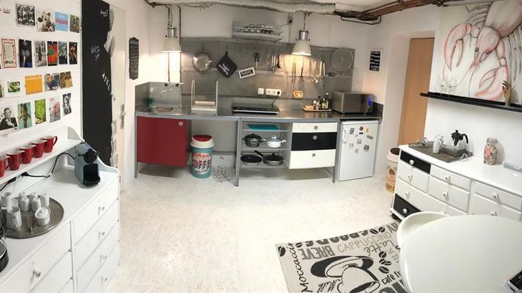 Een moderne keuken met roestvrijstalen apparaten en veel kasten. Aan de muur hangen foto's en ansichtkaarten die de ruimte een creatieve touch geven.