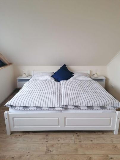 A cozy bedroom with a large bed and striped bedcovers. Next to the bed are two nightstands with lamps.