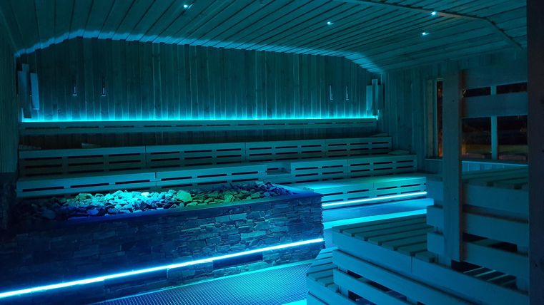 A modern sauna interior with blue LED lights and wooden shelves. The relaxing atmosphere invites you to unwind.