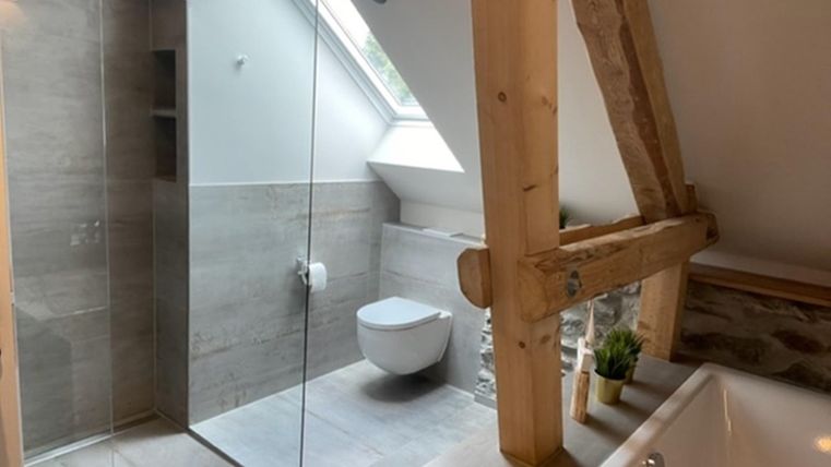 Een moderne badkamer met een glazen douche en een vrijstaand bad. De houtstructuur geeft de ruimte een warme, uitnodigende sfeer.
