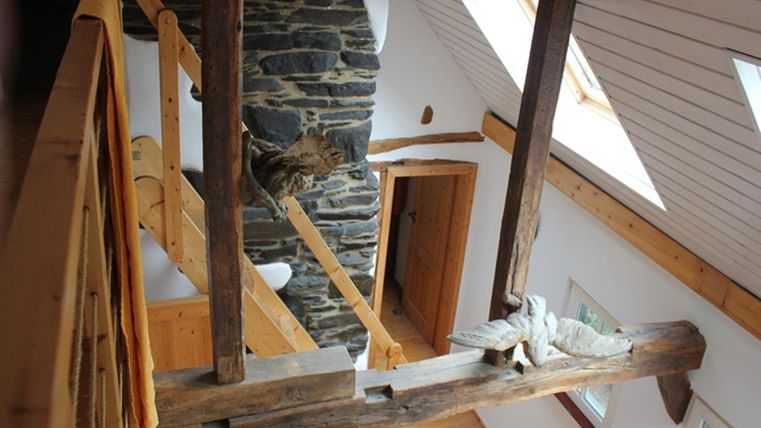 A bright, modern chalet with wooden beams and a stone fireplace. The space has large windows and an inviting atmosphere.