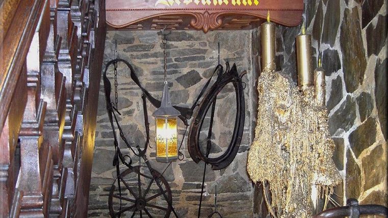Ein gemütlicher Eingangsbereich zu einem Restaurant mit rustikalem Ambiente. Die Wände sind mit Steinen verkleidet und nostalgische Dekorationen hängen von der Decke.