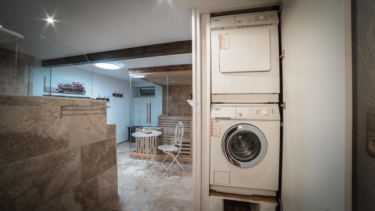 Een moderne wasruimte met wasmachine en droger. De ruimte is stijlvol ingericht en goed verlicht.