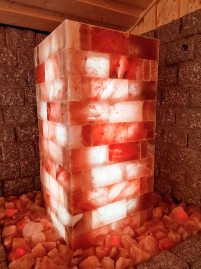 A large block of pink salt that is illuminated from within. Smaller pieces of salt are scattered around the block on the floor.