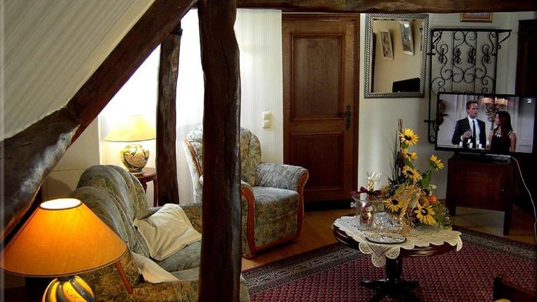 Ein gemütliches Wohnzimmer mit Holzdetails, einem Fernseher und einer Tischdekoration aus Blumen. Es gibt einen Sessel, eine Couch und einen Lampen auf dem Tisch.