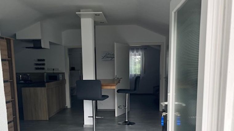 Een moderne keuken met barkrukken en een lichte interieur. De ruimte is goed verlicht en vriendelijk ingericht.