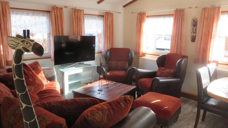 Ein gemütliches Wohnzimmer mit roten und braunen Möbeln. Ein Fernseher und ein Tisch runden die Einrichtung ab.