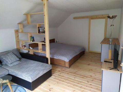 A modern room with a double bed and a seating area. The wooden shelves and the elegant wooden floor create a cozy atmosphere.