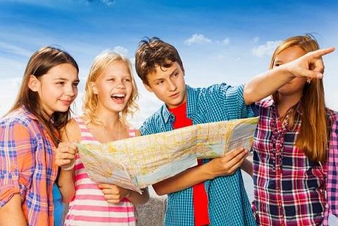 Een groep van vier jonge mensen kijkt naar een landkaart en lacht. Een van hen wijst naar een punt op de kaart.