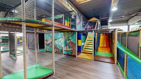 Ein großer Spielplatz mit verschiedenen Rutschen und Kletterelementen. Die bunten Bereiche laden Kinder zum Spielen und Entdecken ein.