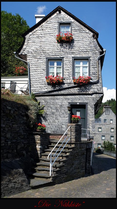 A charming stone house with blooming flower boxes at the windows. The surroundings are quiet and green, perfect for a cozy stroll.