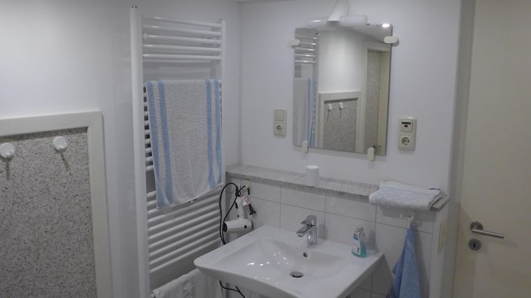 A modern bathroom with a sink and a mirror. Towels hang on the wall and a pleasant lighting creates an inviting atmosphere.