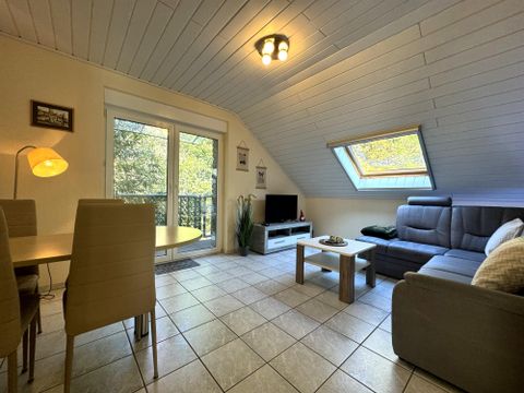 Helder woonkamers met een comfortabele bank en een eettafel. Grote ramen zorgen voor veel daglicht en een aangename sfeer.