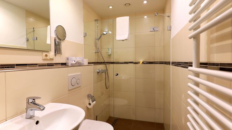 A modern bathroom with a shower and a sink. Bright tiles and a pleasant atmosphere characterize the space.
