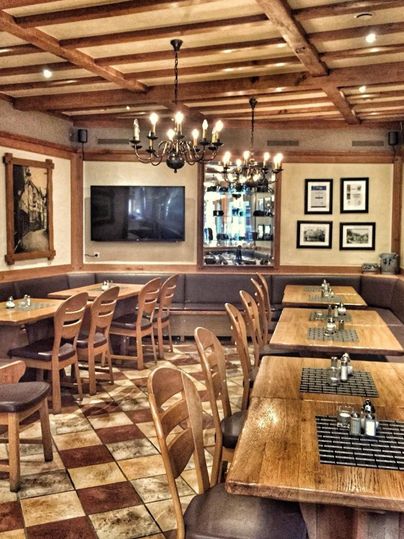Een gezellig restaurant met houten meubels en warm licht. De tafels zijn keurig gedekt en de muren zijn versierd met foto's.