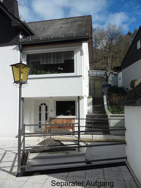 Een modern huis met een aparte ingang en een trap. Voor het huis bevindt zich een kleine zithoek.