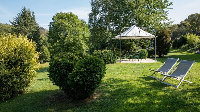 Een groene wei met struiken en een prieel. Twee ligstoelen nodigen uit om te ontspannen.
