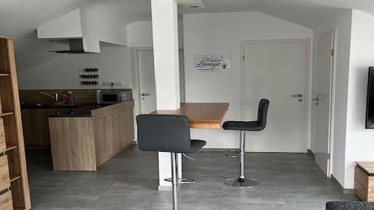 Een moderne keuken met eetgedeelte en barstoelen. De ruimte heeft lichte muren en een open, uitnodigende karakter.