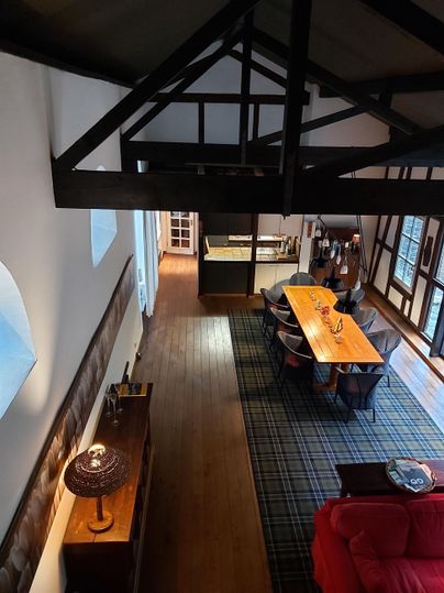 An elegant apartment with wooden floors and high ceilings. The room is modernly furnished with a large table and a cozy couch.