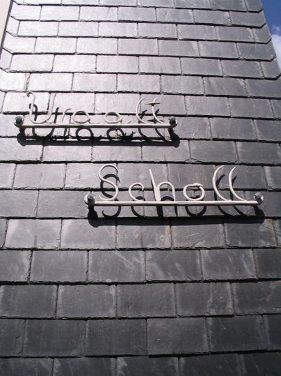 A black roof with two neon-like signs. One displays the text "Clock" and the other "School".