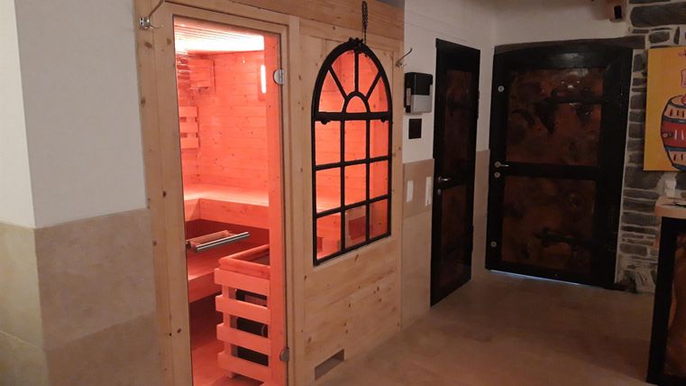 Een gezellige kamer met een sauna en donkere deuren. De sauna is van hout en verlicht met een warme, rode gloed.